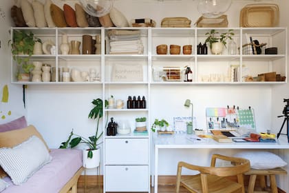 En el entrepiso funciona el estudio de Mariana: desde allí lleva adelante Bonhomia Haus, el proyecto que crearon junto a su socia Agustina Testoni. Además de espacio de trabajo, el ambiente funciona como pequeño showroom. Sillón-cama con fundas y almohadones (Bonhomía Haus). Silla ‘Denmark’ y todos los objetos exhibidos en el mueble (Bonhomía Haus). Modular de hierro (MF Herrería).