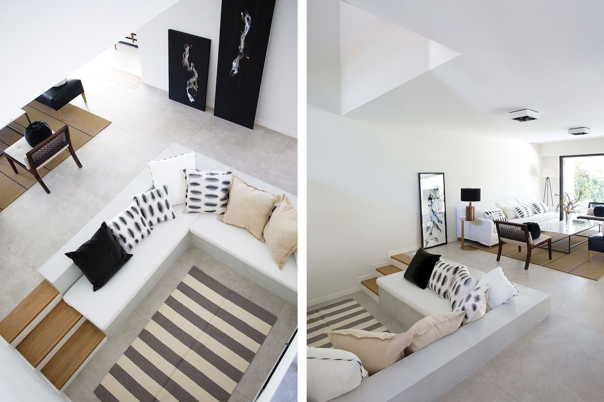 Fotos de un living con chimenea y baco hecho en obra con almohadones y alfombra rayada.