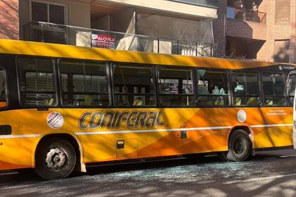 Fragmentos de vidrio en la vereda junto al colectivo dañado