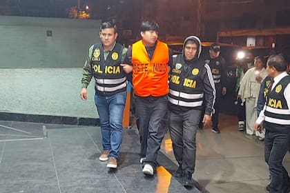 Frame grab from video footage by AFP TV shows the suspected mastermind behind the brutal murders of three young women in a live-streamed attack in Argentina, identified as "Pequeño J," escorted by police officers arriving at the Peruvian police Anti-Drug HQ in Lima on September 30, 2025. The suspected mastermind, Tony Janzen Valverde, "Pequeño J," is a Peruvian national, about 20 years old, and is alleged to operate a drug gang in the Zavaleta neighborhood of Buenos Aires. (Photo by Carlos MANDUJANO / AFPTV / AFP)