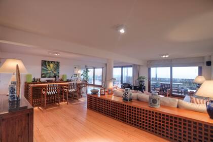 Una imagen del amplio living con sus enormes ventanales que dan al mar. En la casa hay muchos portarretratos con fotos de sus hijos y nietos