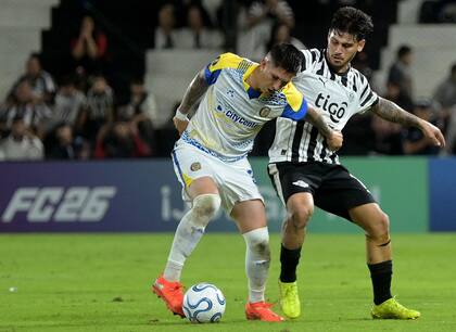 Franco Ibarra, la figura de Rosario Central, protege la pelota ante Matías Espinoza: el volante fue la guía de los canallas en Asunción