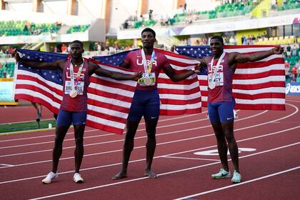 Fred Kerley (centro), ganador del oro en los 100 metros, posa junto a sus compatriotas estadounidenses Marvin Bracy (derecha) y Trayvon Bromell, quienes ganaron respectivamente la plata y el bronce en el Mundial de Atletismo, el sábado 16 de julio de 2022, en Eugene, Oregon (AP Foto/Ashley Landis)