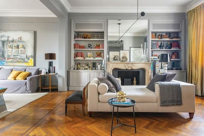 En el living del arquitecto Marcelo Williams, frente a chimenea estilo Luis XV que compró en una remate y una fantástica chaise longue diseñada por él mismo. Los accesorios grises, a tono con las paredes.