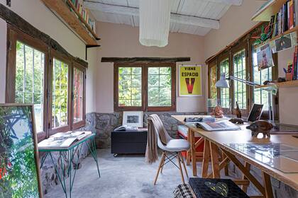 Frente a la mesa de trabajo, silla diseño Eames con patas de madera.