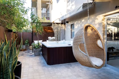 En un patio la hamaca colgante, la pérgola, el jacuzzi y el toldo junto a las macetas y plantas, generan un microclima