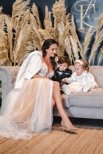 Frente al logo con las iniciales de su nombre y las de Gonzalez, Luciana se toma un descanso con sus hijos.