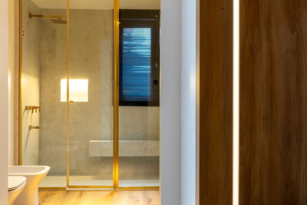 Frente de ducha Shawer Door en el Espacio 201 (estudio C’est Moi): cristal incoloro, perfilería dorada y deslizamiento suave que combinan elegancia y máxima luminosidad.