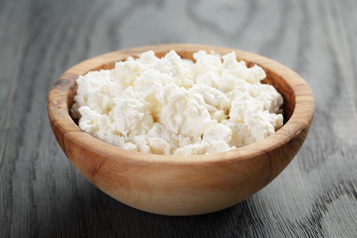 fresh ricotta in olive wood bowl on old table