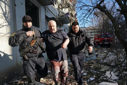Fuerzas de seguridad ucranianas trasladan a un hombre herido después de que un ataque aéreo en un complejo de departamentos en Chuhuiv, Óblast de Kharkiv