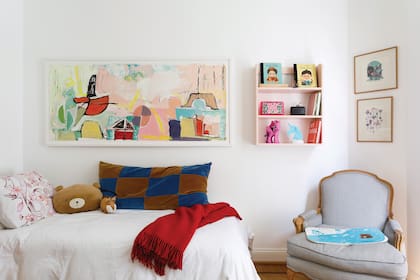 Funcional sin descuidar la estética, para el cuarto de Mía se eligió una mesa de juego con sillitas (El Yeite) en distintos colores. El cuadro sobre la cama es de Flavia Martini; los almohadones de terciopelo, un diseño de su mamá.