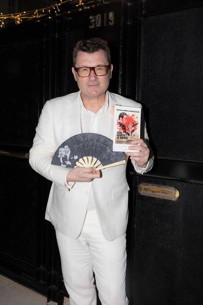 Gabriel Oliveri muestra la tarjeta que le tocó para saber su ubicación en la mesa (tiene impreso un póster de una de las películas de Mirtha) y un abanico con una foto de Chiquita donde se lee “Porque yo ya soy una leyenda”.