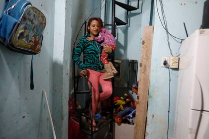 Gabriela junto a su hija más pequeña a upa, en su casa de Barracas.