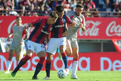 Gastón Campi y Gastón Hernández defienden la pelota ante Mauro Méndez, en el empate entre San Lorenzo y Estudiantes de La Plata por la Copa de la Liga