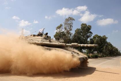 Un tanque de batalla Merkava del ejército israelí cruza una calle mientras se mueve en un convoy a lo largo de la frontera con la Franja de Gaza en el sur de Israel el 13 de octubre de 2023