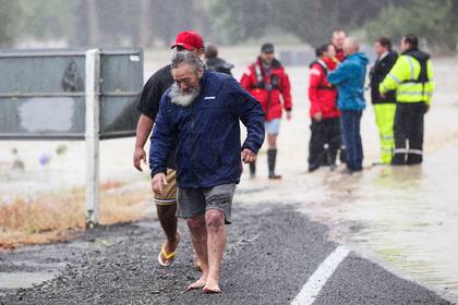 Gente alejándose de aguas crecidas en Hastings, en el sureste de Auckland, Nueva Zelanda, el martes 14 de febrero de 2023. El gobierno de Nueva Zelanda declaró el estado de emergencia en la Isla Norte del país tras el paso del ciclón Gabrielle. (Paul Taylor /Hawkes Bay Today via AP)