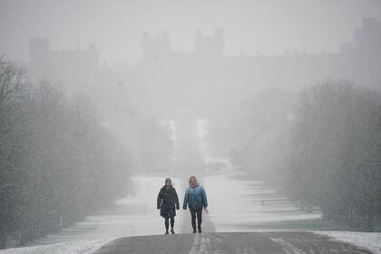 Gente camina entre la nieve por el Long Walk hacia el castillo de Windsor, Berkshire, Inglaterra, miércoles 8 de marzo de 2023. (Yui Mok/PA via AP)