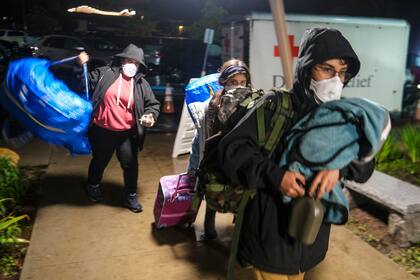 Gente carga sus pertenencias a su llegada a un centro de evacuación en Santa Bárbara, California, el lunes 9 de enero de 2023. (AP Foto/Ringo H.W. Chiu)