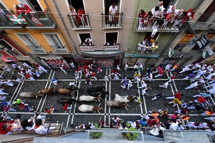 Gente corriendo en la calle junto a toros y bueyes mansos en las Fiestas de San Fermín en Pamplona, en el norte de España, el domingo 10 de julio de 2022. (AP Foto/Álvaro Barrientos)