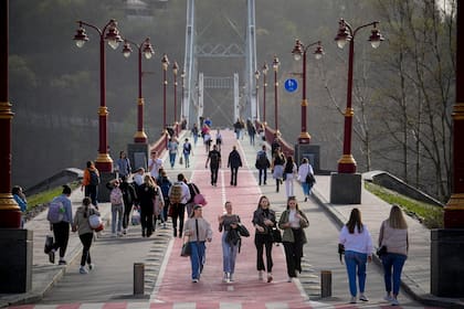 Gente cruzando un puente en una tarde cálida a la orilla del río Dniéper en Kiev, Ucrania (AP Foto/Vadim Ghirda)