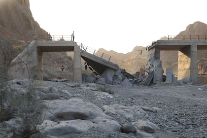 Gente de pie en un puente destruido tras un ataque en lap provincia de Hormozgan, en el sur de Irán