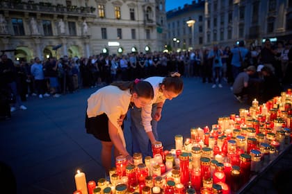 Gente enciende velas por las víctimas de un exalumno que hizo disparos en una escuela, donde mató a varias personas e hirió a muchas otras antes de suicidarse, en Graz, Austria, el martes 10 de junio de 2025. (AP Foto/Darko Bandic)