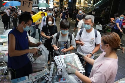 Gente haciendo fila para comprar el último número del diario Apple Daily en un puesto de periódicos en una calle del centro de Hong Kong, el martes 24 de junio de 2021. (AP foto/Vincent Yu)