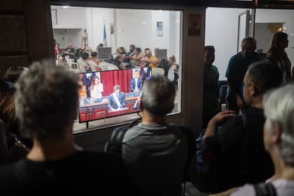 Gente mira un discurso de Milei en televisión
