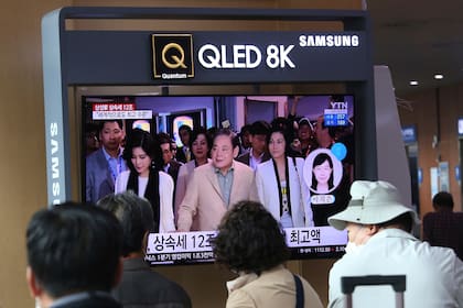 Gente mira un televisor con una imagen del fallecido presidente de Samsung, Lee Kun-Hee, junto a sus hijas en el subte de Seúl