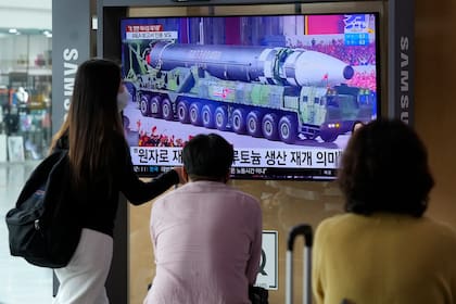 Gente mirando una pantalla de televisión que muestra imágenes de archivo de un misil norcoreano en un desfile militar durante un programa de noticias, en la estación de tren de Seúl, en Corea del Sur, el lunes 30 de agosto de 2021. (AP Foto/Ahn Young-joon)
