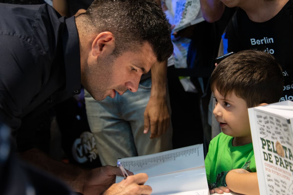 Gigliotti firma un ejemplar de Pelota de Papel 2, bajo la atenta mirada de un pequeño fanático