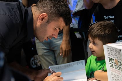 Gigliotti firma un ejemplar de Pelota de Papel 2, bajo la atenta mirada de un pequeño fanático