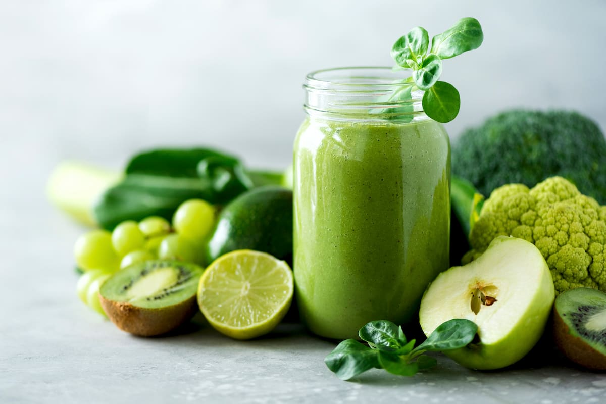 Glass jar mugs with green health smoothie, kale leaves, lime, apple, kiwi, grapes, banana, avocado, lettuce. Copy space. Raw, vegan, vegetarian, alkaline food concept. Banner.