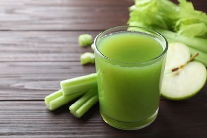 Glass of celery juice and fresh ingredients on wooden table, closeup
