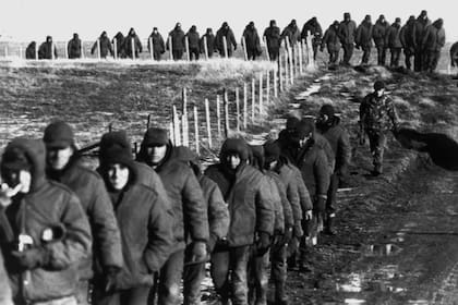 Soldados argentinos (en primer plano) son escoltados por soldados británicos después de rendirse el 2 de junio de 1982 cerca de Goose Green durante la guerra de las Islas Malvinas.