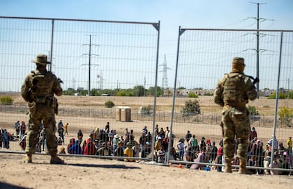 Gran cantidad de migrantes aguardan junto a la cerca fronteriza para entrar en El Paso, Texas, ante la mirada de miembros de la Guardia Nacional del estado. (AP Foto/Andrés Leighton, archivo)