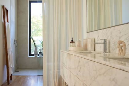 Grifería de baño (Porcelanosa). Sobre la mesada de mármol ‘Calacatta’, floreros (Edition Tupé).