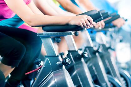 Group of four people biking in the gym, exercising their legs doing cardio training