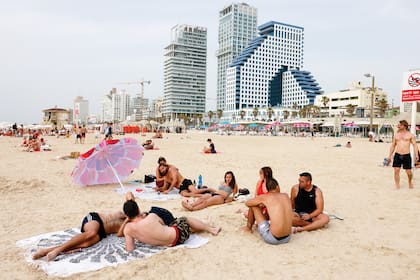 Grupos de gente en las playas de Tel Aviv; en Israel ya no rige la obligatoriedad de tapabocas y demás medidas contra la pandemia tras una masiva campaña de vacunación