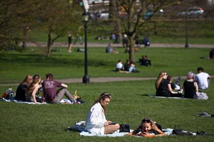 Grupos de personas se sientan y charlan juntas en el clima cálido de Primrose Hill en Londres el 29 de marzo de 2021, cuando se alivian las restricciones de bloqueo en Inglaterra, lo que permite que grupos de hasta seis personas se reúnan afuera