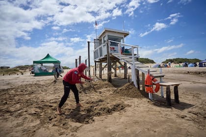 Guardavidas refuerzan con arena la base de su casilla en una playa de Cariló