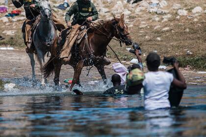 Guardias fronterizos a caballo tratan de impedir el paso de migrantes que cruzan el río Bravo desde Ciudad Acuña, México, a Del Rio, Texas, 19 de setiembre de 2021. (AP Foto/Felix Marquez)