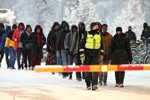 Guardias fronterizos finlandeses escoltan a migrantes en el cruce internacional entre Finlandia y Rusia, en Salla, Finlandia, el 23 de noviembre de 2023. (Jussi Nukari/Lehtikuva via AP)