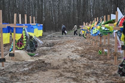 Residentes caminan junto a las tumbas de un cementerio en Chernigiv, en el norte de Ucrania, el 5 de abril de 2022. Las autoridades de la ciudad calculan que unos 350 civiles han muerto en Chernigiv desde el comienzo de la invasión rusa.