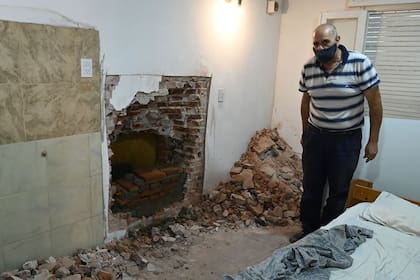 Guillermo Algañaraz, de 62 años, expone el boquete usado por los ladrones para ingresar desde su casa a una empresa de caudales