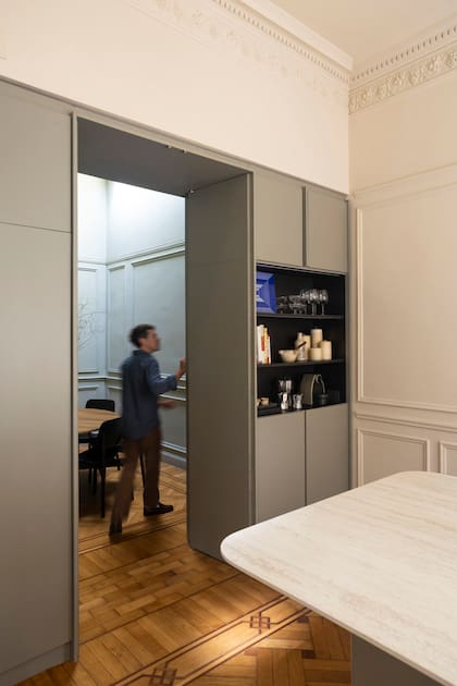Hacia el comedor, el mueble diseñado por el Estudio es cava y vajillero; hacia la cocina, coffee station y alacena. En su parte superior, esconde el sistema de climatización.