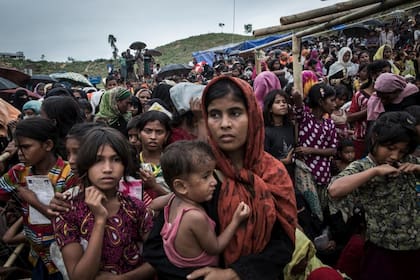 Hamida, de 22 años, (centro) y su hijo Mohammed, de 1 año, esperan recibir ayuda alimentaria junto con otros cientos de refugiados rohingyas en el campo de refugiados de Kutupalong