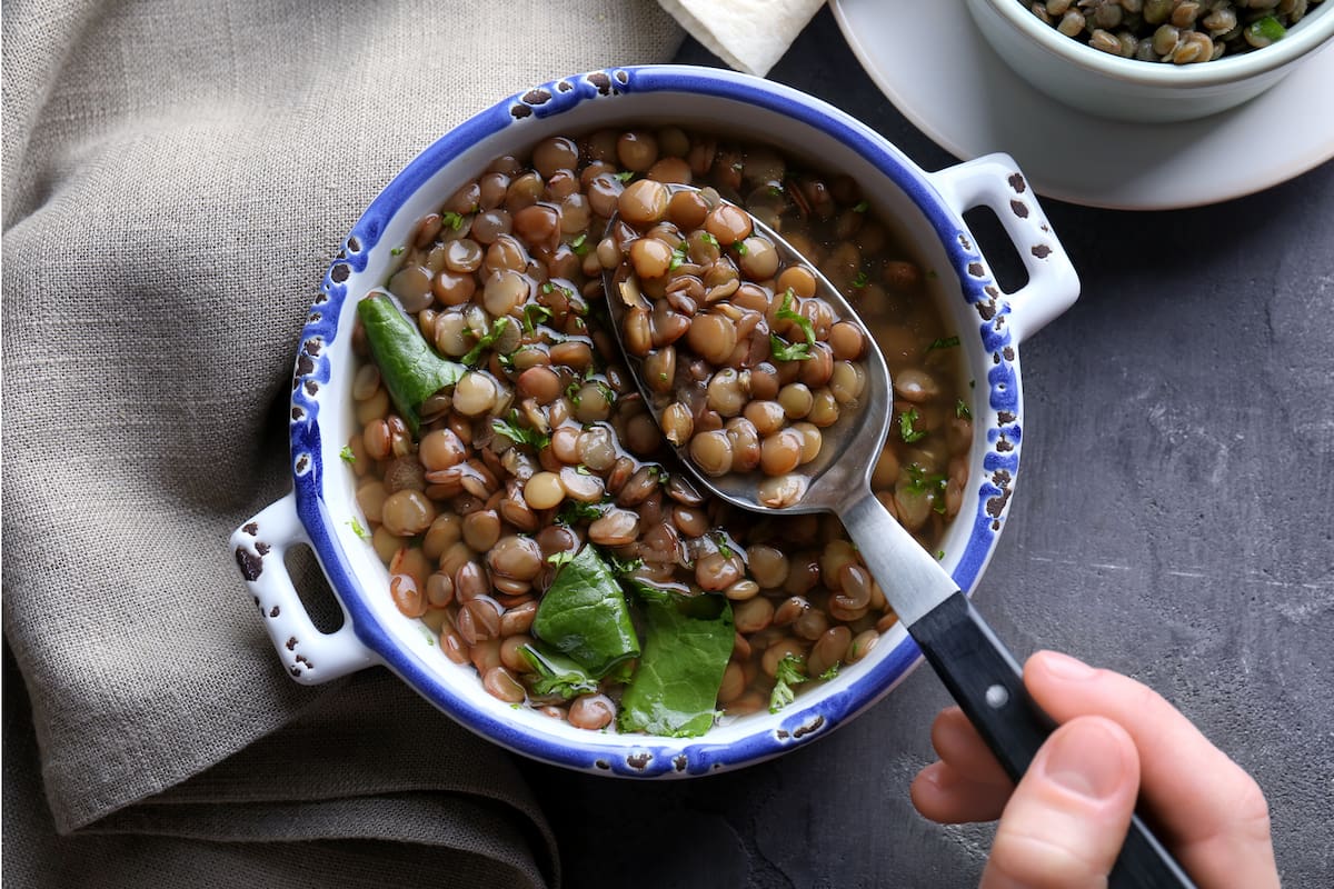 Hand of woman eating tasty lentil dish, closeup