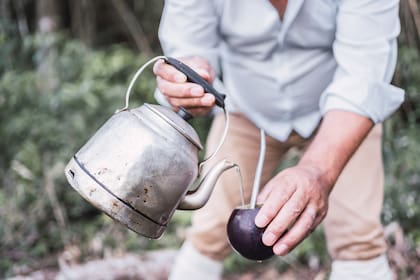 Hands holding mate and teapot to drink yerba mate Argentinean tradition.