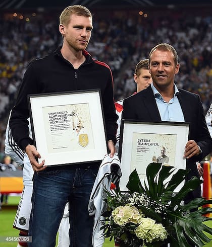 Hansi Flick con Mertesacker, a quien le explicó los motivos por los que quedó fuera de un partido importante en el Mundial 2014.